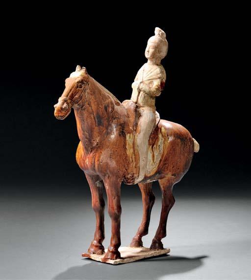 $15,000-20,000 46 Pottery Horse and Rider, China, Tang dynasty-style, the rider with her hands folded across her chest, wearing a cream-glazed robe with unglazed face and legs, the horse decorated