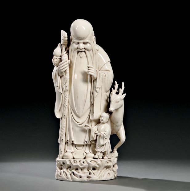 101 101 Large Blanc-de-Chine Figure of Shoulao, China, early 20th century, standing with a staff in his right hand, accompanied by a boy and deer, a Dehua gourd-shaped seal mark and four-character