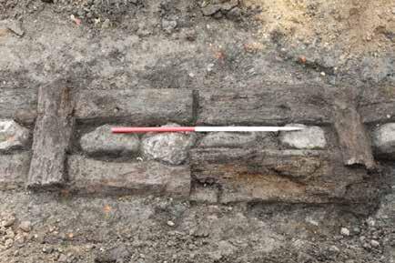 Figure 94 Part of the timber and stone foundation Cross-pieces were also seen; these were shorter wooden pieces that linked the two sides of the timber linear foundations, and it may be that it was