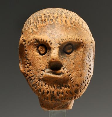 An incised moustache between mouth and nose that is interpreted as fur zone. The hair is rendered by short incised lines along the rim of the circle.