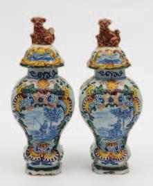 428 428 A pair of Dutch polychrome Delft jars and covers of inverted pear shaped form, the domed covers with seated animal knops, the vases painted in blue, yellow, green and aubergine with a panel