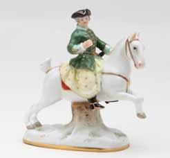 15. A Kloster Veilsdorf porcelain figure of a sportsman, standing, wearing a patterned waistcoat and rust trimmed hunting coat, with black broad brimmed hat, a game bag and gun over his shoulder, on