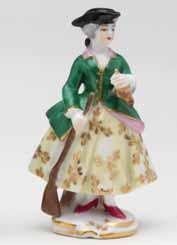 22. A Dresden miniature figure of a sportswoman, standing, wearing a yellow skirt, puce and gilt trimmed green hunting coat and