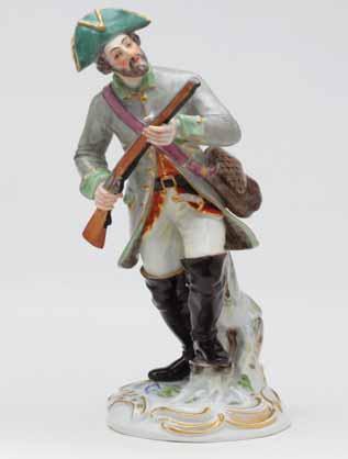 A Meissen figure of a bearded sportsman, standing, wearing a pale green hunting coat, and gilt trimmed green tricorn hat, a game bag over his