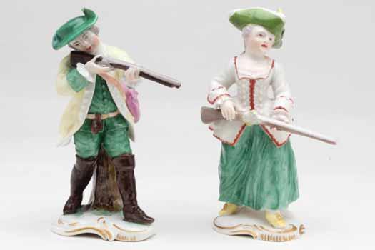 46. A pair of Frankenthal small figures of a sportsman and woman, he wearing green breeches, a pale yellow hunting coat and green hat, and taking aim with a gun to his right shoulder, and she in