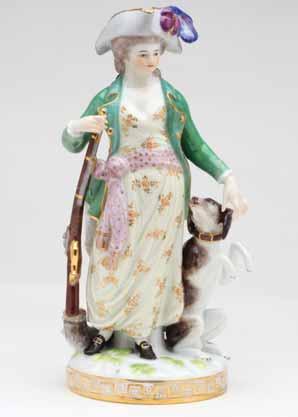 A Meissen figure of a sportswoman, standing, wearing a flower patterned dress, tied with a sash, a green hunting coat, and a plumed gilt trimmed