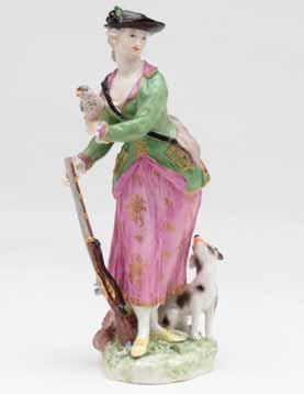 50. A Ludwigsburg figure of a sportswoman, standing, wearing a pale skirt, orange and gilt trimmed green hunting coat and brown hat, holding a bird in her left hand, and a gun in her right, a