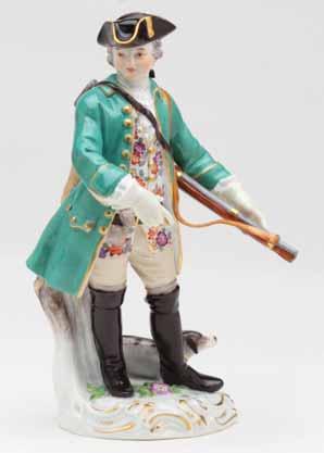 54. A Meissen figure of a sportsman, standing, wearing a flower patterned waistcoat, turquoise hunting coat and gilt trimmed black tricorn hat, a gun