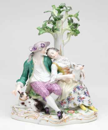 3. A Meissen group of a shepherd and shepherdess, seated before a tree, he with a hound and she with a lamb, decorated in coloured enamels, the flower applied and