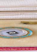 mother-of-pearl disc, inset with an old brilliantcut diamond, within a frame of light blue enamel,