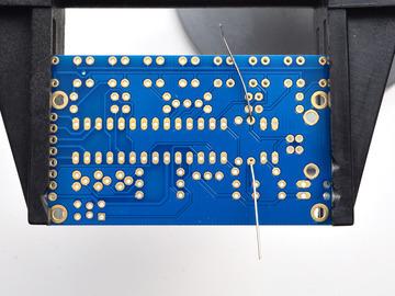Bend the resistor into a staple and slip it onto the top of the Printed Circuit Board.