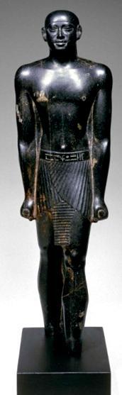 It is carved from a black stone and hs an 0.435 m height. The owner is shown wearing a medium Schenti with belt and a tight cap headdress.