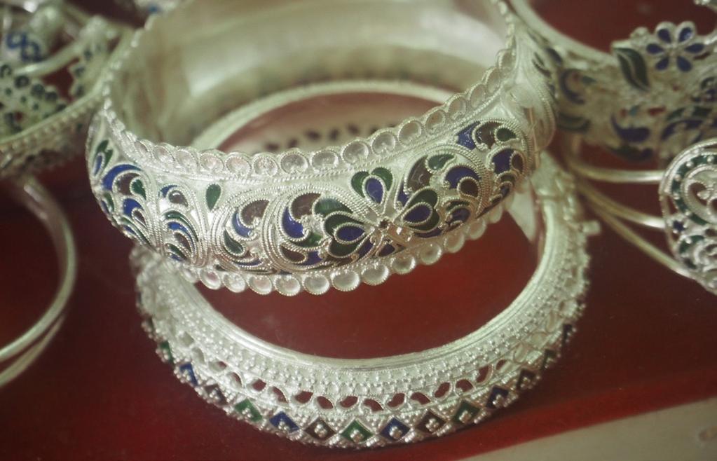 Their production primarily employs carved beads and unique local shapes such as a Dok Takao, a Khmer name for a flat circular silver piece with jagged edges similar to the sun.
