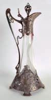150-200 335 GERMAN ART NOUVEAU SILVER AND GLASS CLARET JUG decorated with neo classical female portraits, the handle of organic form. 1ft 3.5ins high.