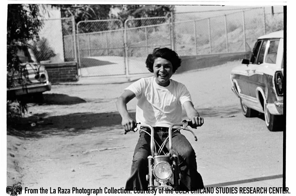 Boy on a motorcycle La Raza photograph collection.