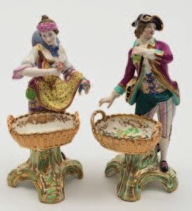 300-500 649 A pair of Minton figures of flower and fruit sellers the gallant and lady holding a bunch of grapes and bunches of flowers respectively, each with a twohandled wicker basket below and on