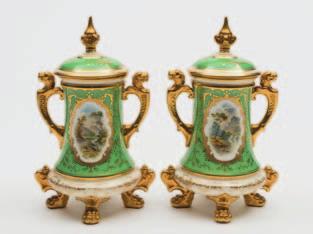 671 A pair of Coalport porcelain jars and covers of tapering cylindrical form set on four lion paw feet, the handles with animal mask terminals, the domed covers with spire knops, each decorated by