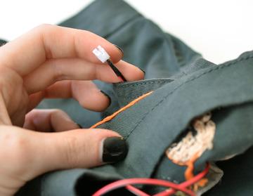 Tack down the extension cable on the back of the embroidery, using stitches or just a very few fibers on the fabric to anchor it with plain thread.