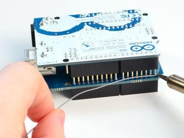 Carefully remove the shield from the Arduino and place flat on the table, long pins sticking up Adafruit