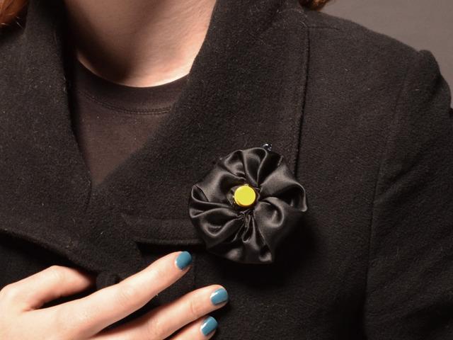 Wear it This Flora TV-B-Gone is made to look like a black flower with a yellow center.