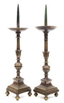 717 717 A matched pair of bronze pricket candlesticks of traditional design with circular drip trays on a knopped and petal decorated stem, raised on a triangular base