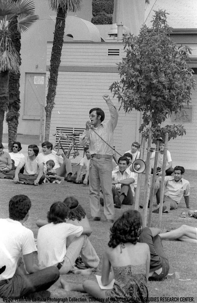 Man, possibly Nacho Uribe, speaks to a crowd at Chicano Moratorium anniversary Patricia