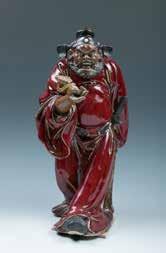 132 A SHIWAN GLAZED POTTERY ZHONGKUI FIGURE 钟馗接福石湾人物像 A Shiwan glazed pottery walking figure, depiction a burly man holding a Ruyi
