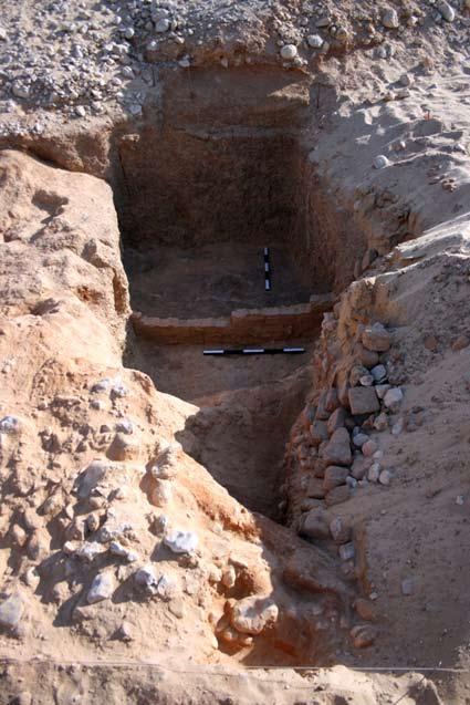 Figure 8. The deep pit, fronted by a partially preserved brick wall, exposed in Trench 7. Facing south. vertically out of the plateau edge, a sand-filled hollow covering the intervening ground.