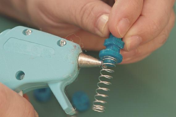 Use a good coating of hot-glue to hold the spring to the post. Grab another spring and post - repeat.