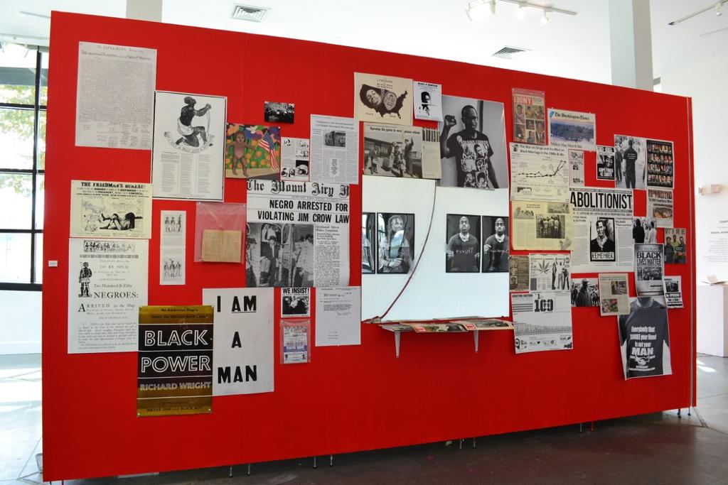Across from these photographic portraits is an installation called Perceptions consisting of pinned vintage magazines, newspaper articles, reproductions of posters, political ads from the 1860 s, and
