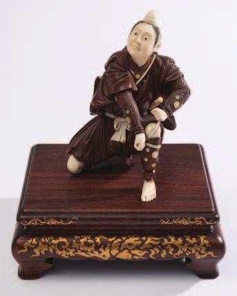 780 781 780 A Japanese ivory and hardwood okimono of a kneeling samurai warrior adjusting his