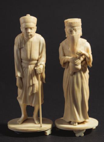 797 795 795 A pair of Burmese carved ivory figures of native male and female figures in traditional dress, on circular ivory stands,