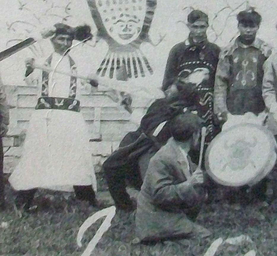 I would like to bring your attention to the ganhooks or ceremonial dance sticks held by the man on the far left and by the person on the far right.