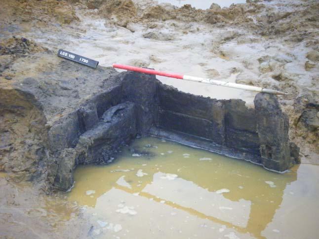 Plate 8 Water tank 1219 (pit 1172), assembled from recycled section of boat, during excavation looking north. The horizontal scale is 2m long Plate 8.
