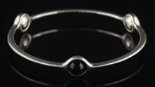A sterling silver sphere bangle designed by Regitze Overgaard for Georg Jensen, the bangle set with three cabochon gem stones and