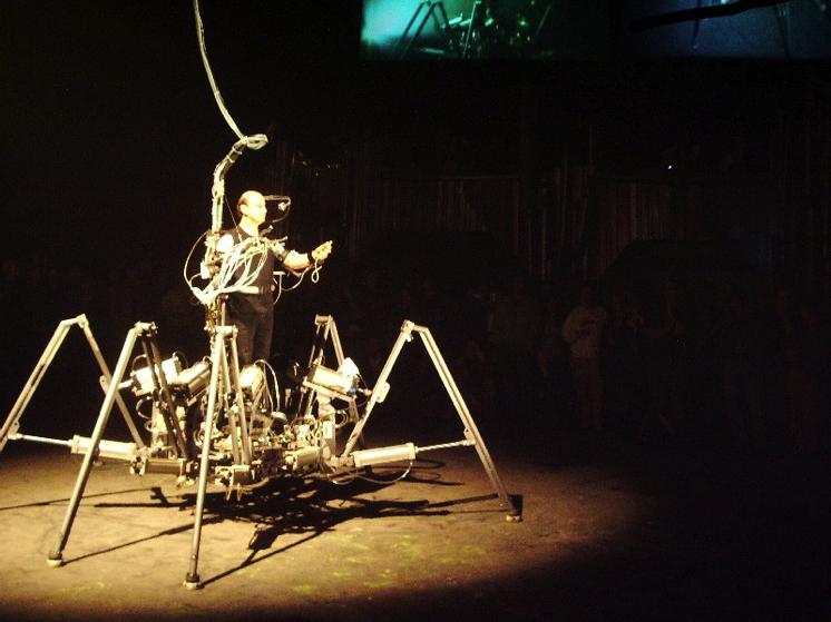 Stelark Exoskeleton,1998 He performed with a robotic third arm, and a pneumatic spider-like six-legged walking machine, which sits the user in