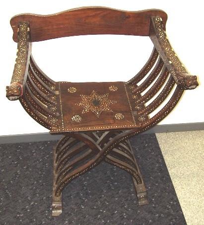 Furniture 2005.731 Chair Wood, bone / hand-crafted Large ornate wooden chair, flat back panel (new) and seat, perpendicular arms with five symmetrical curved ribs crossing under chair to form legs.