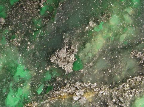 Figure 10. Microscopic examination of the cabochons revealed patches of pyrite and massive green cloud-like areas, while the host chalcedony appeared light gray. Photomicrograph by W. L.
