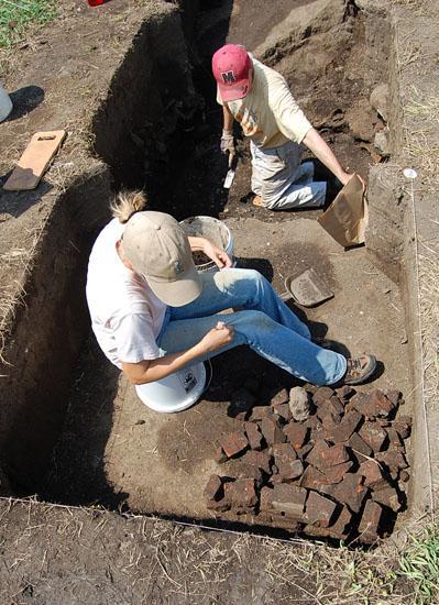 Figure 4.5. Terry Martin and Kathrine Hardcastle of Team Z excavate Feature 28. Next to Kathrine is a sample of the brick fragments included within Feature 28 (Photograph by Joe Conover).