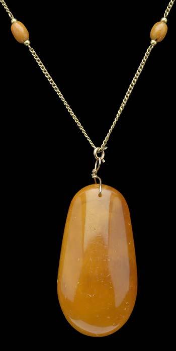 110 AN AMBER SET LONG CHAIN NECKLACE WITH LARGE AMBER PENDANT DROP, the fine 9ct gold curb-link chain spaced with oval polished amber beads, suspending a large oval amber pendant below, with wirework